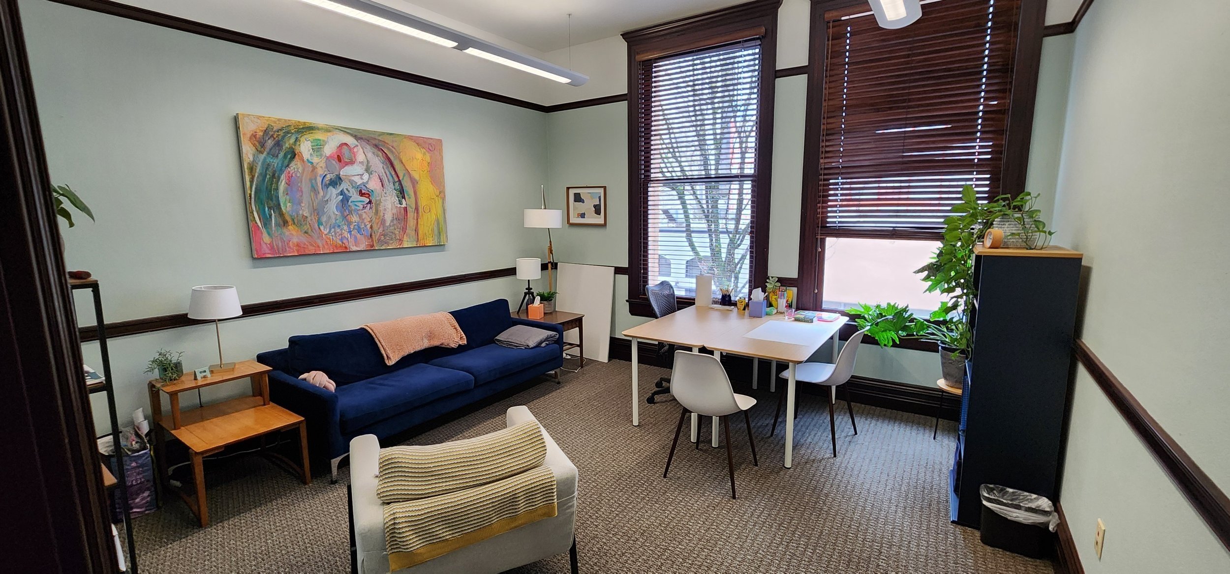 Private therapy office with seating, desk, and natural light